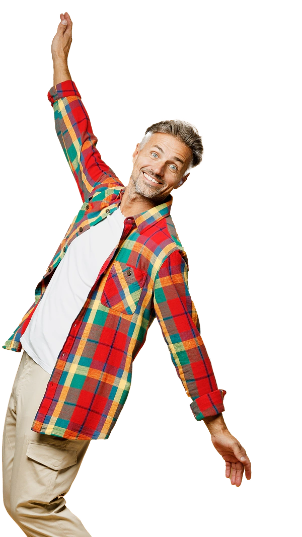 Zdjęcie przedstawiające uśmiechniętego mężczyznę w kolorowej, kraciastej koszuli, białym t-shircie i beżowych spodniach, pozującego z podniesioną ręką na jasnym tle.